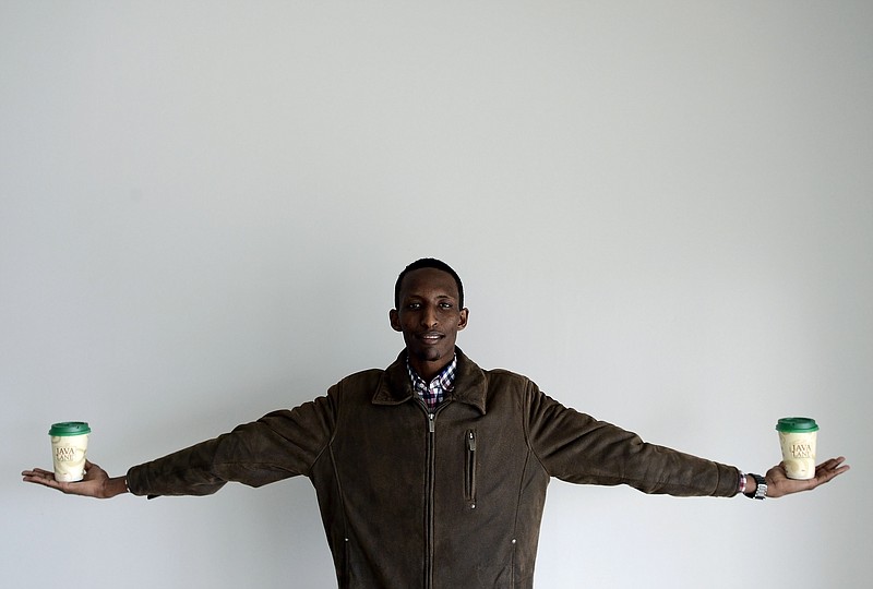 
              Som Cafe owner Mohamed-Shukri Hassan holds two coffee cups in each of his hands at his newly opened second location, The Horn Coffee shop, on Wednesday, March 11, 2015, in Nashville, Tenn. Hassan, one of the city's top advocates for immigrants, sits on several boards that aid new Americans in Nashville. Plus, he has started a consulting business to help new Americans acclimate.   (AP Photo/The Tennessean, Mark Zaleski)  NO SALES
            