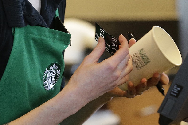 
              FILE - In a Wednesday, March 18, 2015 file photo, Holly Ainslie, a barista at a Starbucks store in Seattle puts a "Race Together" sticker on a customer's cup. Starbucks baristas will no longer write "Race Together" on customers' cups starting Sunday, March 22, 2015, ending as planned a visible component of the company's diversity and racial inequality campaign, according to a memo. The coffee chain's initiative will continue more broadly without the handwritten messages, Starbucks spokesman Jim Olson said.  (AP Photo/Ted S. Warren, File)
            