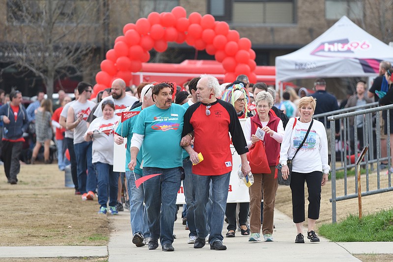 Jim Samples, left, and and Chuck Cagle link arms as they lead walkers at the start of the 20th annual Strides of March Memorial Walk on Sunday, March 22, 2015, in Chattanooga, an event that benefits Chattanooga CARES.