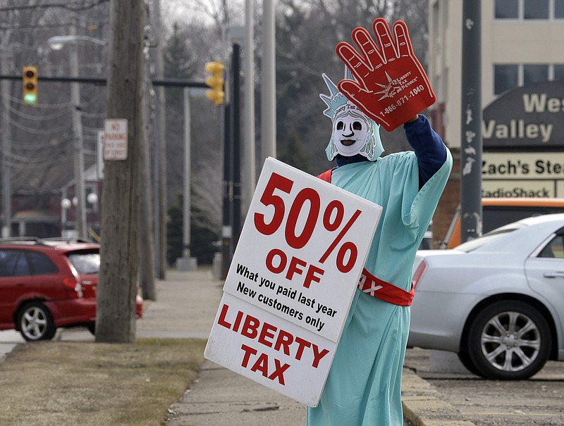 
              In this March 21, 2015 photo, Brittney Freison, dressed as Lady Liberty, waves to motorists near the Liberty Tax Service office in Berea, Ohio. Wary of rising fees, federal regulators are eyeing ways they can assert tighter oversight upon paid tax preparers who cater to an expanding market of cash-strapped families anxious for their tax refunds. (AP Photo/Mark Duncan)
            