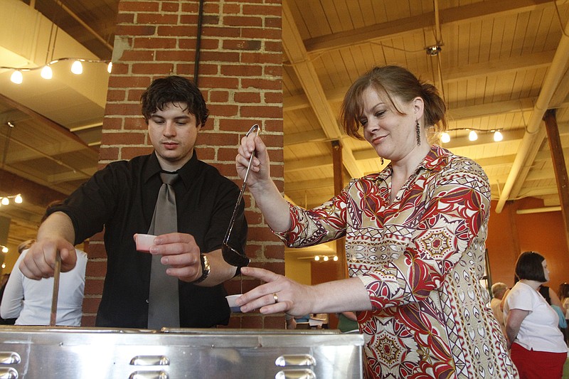 Mark Burton, left, ladles out melted white chocolate infused with passion fruit while Stephanie Majoras fills a cup with melted dark chocolate.