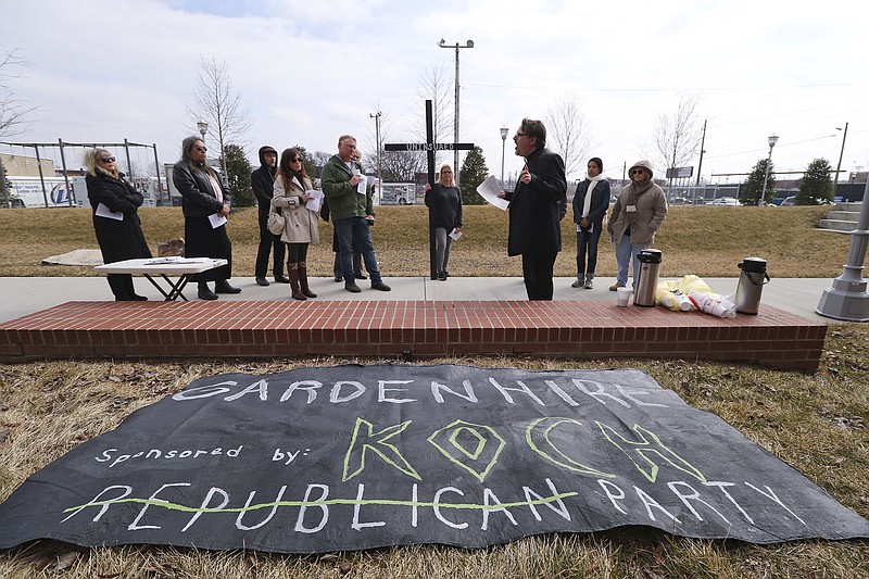 Reverend Brian Merritt leads members of the Mercy Junction Ministry in a protest for the uninsured while staged in The Main Terrain city park adjacent to the Hamilton County Pachyderm Club's luncheon on Monday, February 23, 2015.