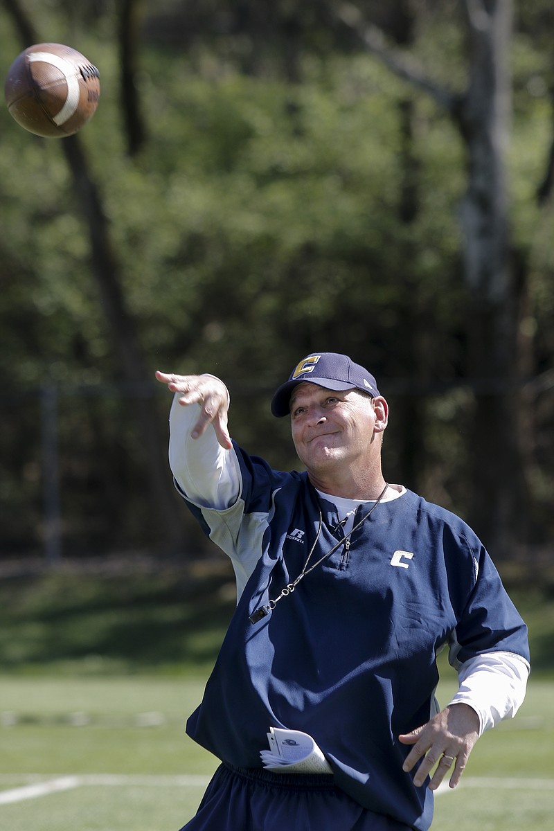 UTC head football coach Russ Huesman warms up his arm during the Mocs' football practice on Wednesday, March 25, 2015, in Chattanooga.