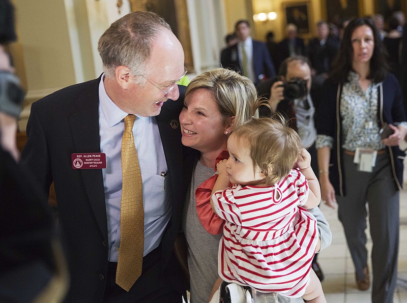 State Rep. Allen Peake, R-Macon, left, celebrates with Kristi Baggarly, holding her daughter Kimber, 1, as they walk through the Capitol after the Senate approved Peake's medical marijuana bill Tuesday, March 24, 2015, in Atlanta.