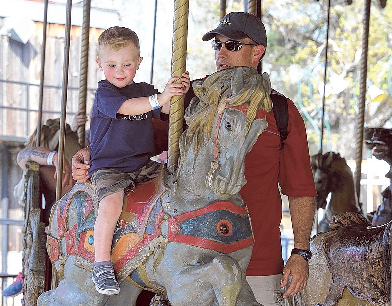 Bradley Brown, 2, rides on the carousel while Donny Brown stands by at Lake Winnepesaukah Amusement Park in Rossville, Ga. 