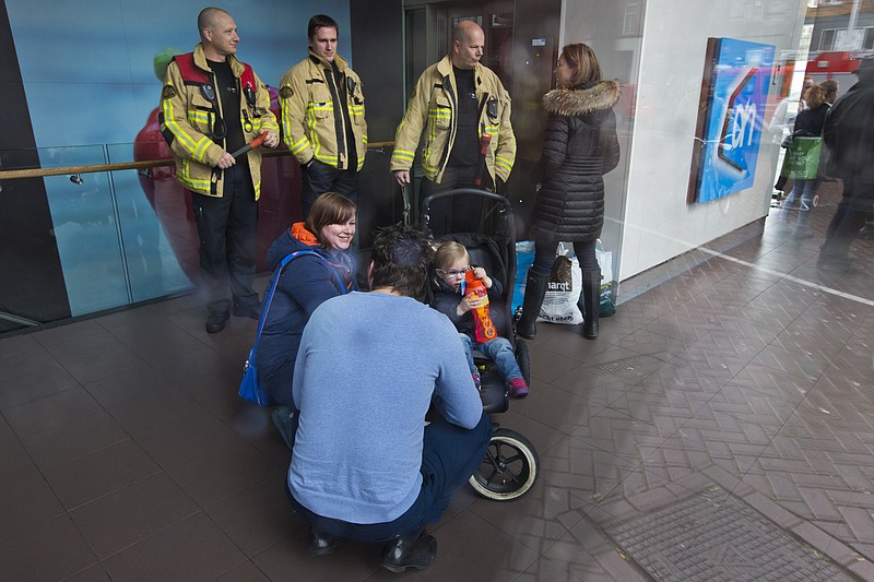 
              A couple comforts a young girl in a stroller after being freed from an elevator by the fire department, rear, during a power outage in Amsterdam, Netherlands, Friday, March 27, 2015. The Dutch capital Amsterdam and surrounding towns suffered a major power outage, halting trains, trams and affecting flights to Schiphol Airport. (AP Photo/Peter Dejong)
            