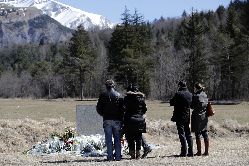 
              People and family members of a victim pay tribute next to a stele and flowers laid in memory of the victims in the area where the Germanwings jetliner crashed in the French Alps, in Le Vernet, France, Friday, March 27, 2015. The crash of Germanwings Flight 9525 into an Alpine mountain, which killed all 150 people aboard, has raised questions about the mental state of the co-pilot. Authorities believe the 27-year-old German deliberately sought to destroy the Airbus A320 as it flew Tuesday from Barcelona to Duesseldorf. (AP Photo/Christophe Ena)
            