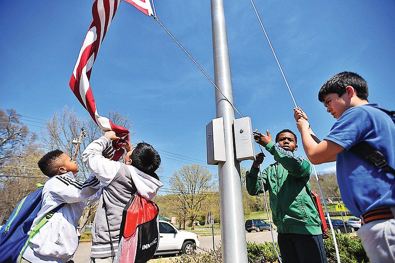 Massi Taylor, Juan Lucas Bautista, Tai Hall and Bryan Rocha, from left, take down the flag Wednesday at East Lake Elementary School.