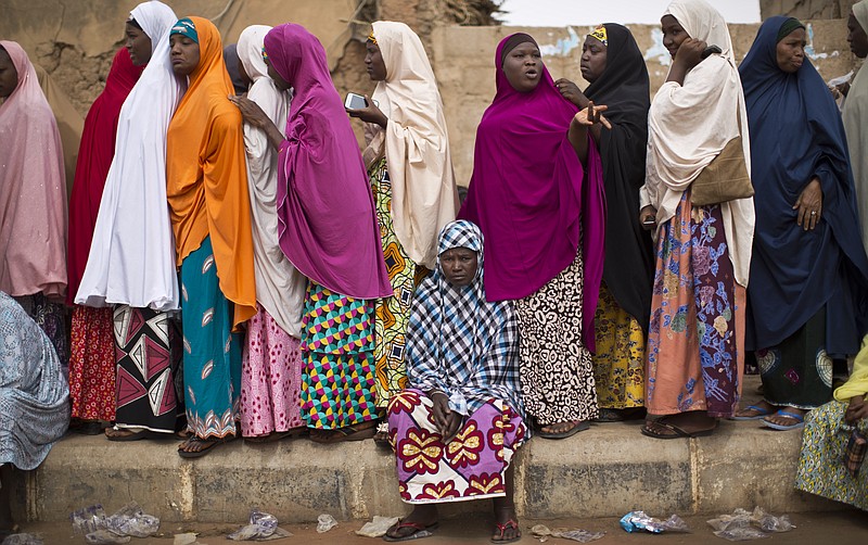 
              A tired Nigerian woman sits down to rest as others queue, while they face long delays to cast their vote in the afternoon at a polling station in Daura, the home town of opposition candidate Gen. Muhammadu Buhari, in northern Nigeria Saturday, March 28, 2015. Nigerians went to the polls Saturday in presidential elections which analysts say will be the most tightly contested in the history of Africa's richest nation and its largest democracy. (AP Photo/Ben Curtis)
            