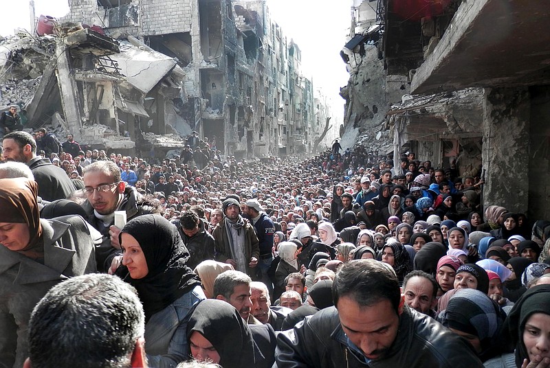 
              FILE - In this Jan. 31, 2014, file photo, released by the United Nations Relief and Works Agency for Palestine Refugees in the Near East (UNRWA), shows residents of the besieged Palestinian camp of Yarmouk, queuing to receive food supplies, in Damascus, Syria. UNRWA spokesman Christopher Gunness says the agency needs around $250 million to fund its cash program, which provides cash distributions for roughly half a million Palestinian refugees affected by the war in Syria. (AP Photo/UNRWA, File)
            