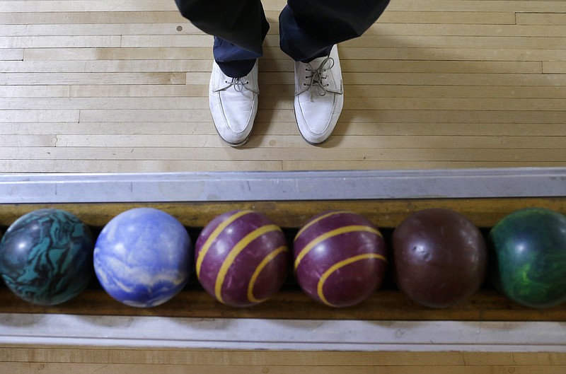 
              Josh Miller stands next to a rack of duckpin bowling balls during a tournament at Shenandoah Bowling Lanes, Saturday, March 28, 2015, in Mount Jackson, Va. The sport, which is mostly played in the Mid-Atlantic, enjoyed its peak in the 1960s. Shenandoah, open since 1948, is one of around 60 remaining duckpin alleys in the United States. (AP Photo/Patrick Semansky)
            