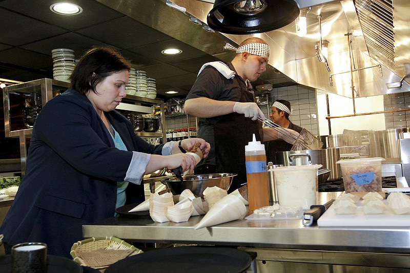 Operating partner Jessica Benefield, left, plates food while chef Chris Maldonado cooks in the kitchen during a VIP event at new restaurant Two Ten Jack located in Warehouse Row in Chattanooga. The restaurant offers ramen dishes and Japanese pub-style food.