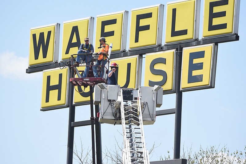 Captain Jim Henegar of the Chattanooga Fire Department uses a ladder truck to rescue Chris Statom, left, and Brandon Nihiser, employees of River City Sign and Neon, after a breakdown on the bucket truck they were using Tuesday, Mar. 31, 2015, in Chattanooga, Tenn. They were attempting to change lights on the 23rd Street Waffle House sign when a mechanical failure stranded them approximately 60 feet in the air, but they were rescued without injury.
