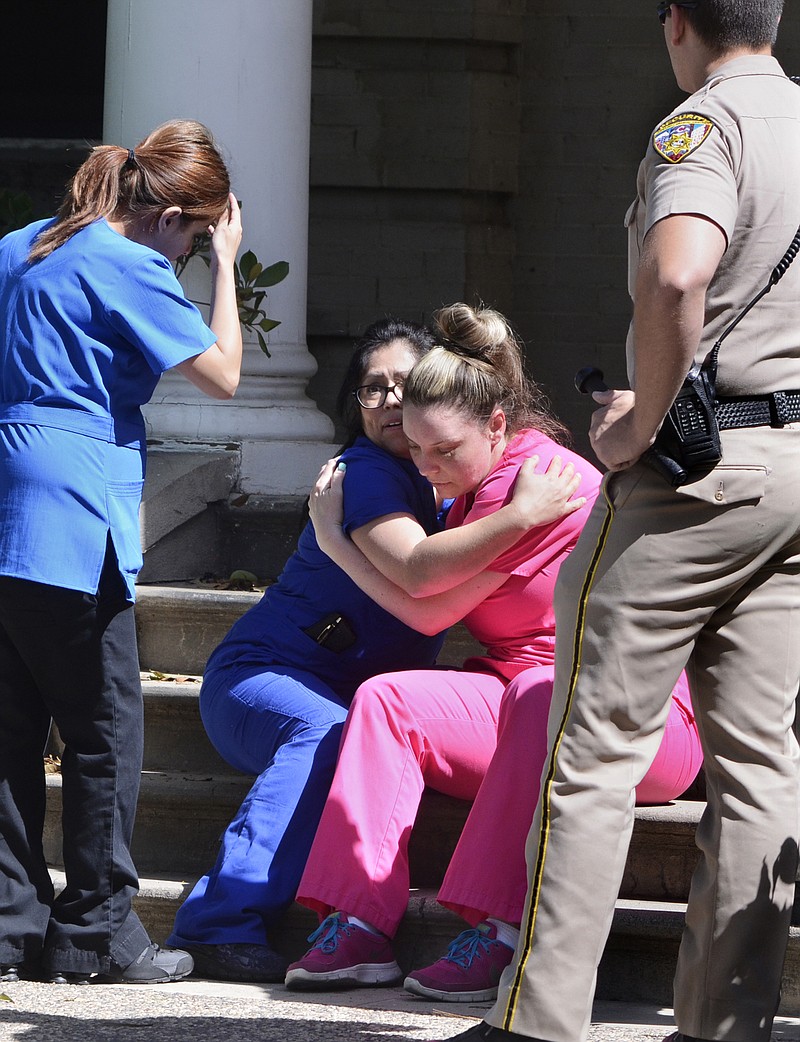 
              Medical personnel comfort each other after being evacuated by Fresno Police at the scene of a shooting at a medical clinic Tuesday, March 31, 2015, in Fresno, Calif. A man and a woman were found dead after a shooting at the Eye Medical Clinic in downtown Fresno, police in central California said. (AP Photo/The Fresno Bee, John Walker)
            