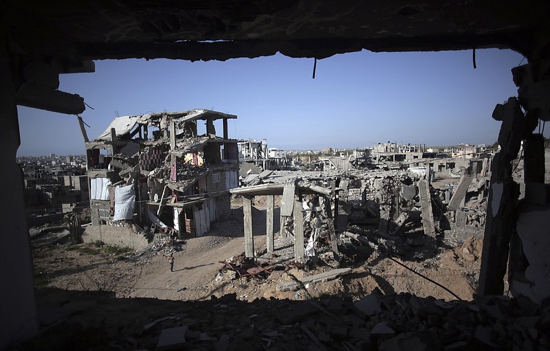 
              A Palestinian girl walks next to destroyed houses, in the Shijaiyah neighborhood of Gaza City, Monday, March 30, 2015. Despondent over the slow pace of post-war reconstruction, displaced Gazans have begun to return to their damaged homes, patching up the structures with blankets and plastic sheets and living in the unstable and unsafe structures while they wait for promised aid to arrive. (AP Photo/Khalil Hamra)
            