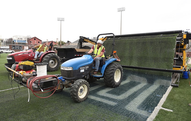 Brian Lee, left, and Ethan Peplow, with Mid-America Sports Construction, remove the infill from the turf at Finley Stadium on March 9, 2015. The infill, which is made from tires, will be recycled.