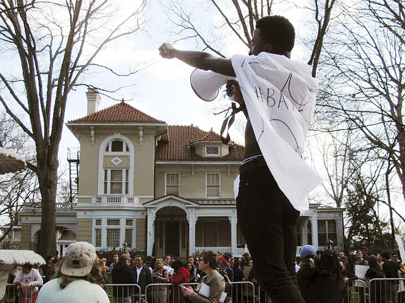 
              In this Tuesday March 31, 2015 photo, Ohio University senior Ryant Taylor fires up the crowd gathered in front of the president’s former residence during a campus rally to protest the university moving President Roderick McDavis to a home off campus. McDavis and his wife relocated last month because of a bat infestation at the century-old house on campus. (AP Photo/Mitch Stacy)
            