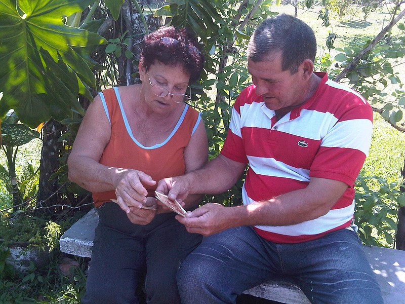 
              In this Friday, March 20, 2015 photo, Fidelia Rodriguez and her son Camilo hold old photos of U.S. citizen Daniel Smith and his family from before the Cuban Revolution in the Isle of Pines, Cuba. Fidelia's father worked as a gardener for the Smiths before the family's property was confiscated by the new government. (AP Photo/Milexy Duran)
            