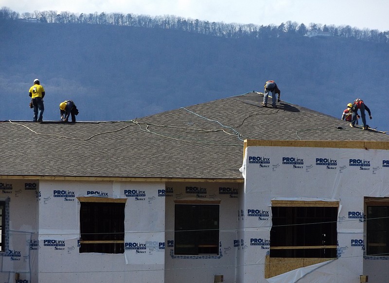 Roofers work to top off one of the buildings at the Cameron Harbor development on the Tennessee River.