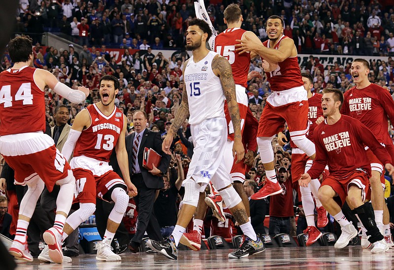 Wisconsin bench celebrates as Kentucky's Willie Cauley-Stein walks off after their NCAA Final Four tournament Saturday, April 4, 2015, in Indianapolis. Wisconsin won 71-64. 