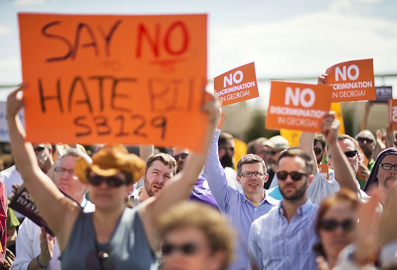 
              FILE- In this March 17, 2015 file photo, protestors hold up signs during a rally against a contentious "religious freedom" bill in Atlanta. The divide within the Georgia Republican Party on a religious free measure came into clear focus at the March rally opposing the bill. “I will not let a small minority of vocal legislators hijack my state,” David Bachman told the crowd outside the Georgia Capitol. Bachman is a 26-year-old gay man who owns a tie-making company and has been involved with Republican campaigns since high school, personifying the split between his party’s business wing and religious backers. The bill failed to get a House vote on Thursday as lawmakers adjourned for the year. It is likely to return in 2016. (AP Photo/David Goldman, File)
            