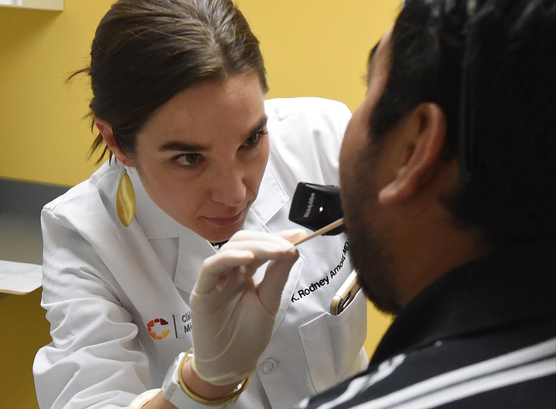 Dr. Kelly Rodney Arnold, M.D., looks at the throat of patient Enrique Gmez at the Clinica Medicos on Holtzclaw Avenue. The facility, open since March 1, is the first comprehensive bilingual medical clinic targeted toward the city's Latino population.