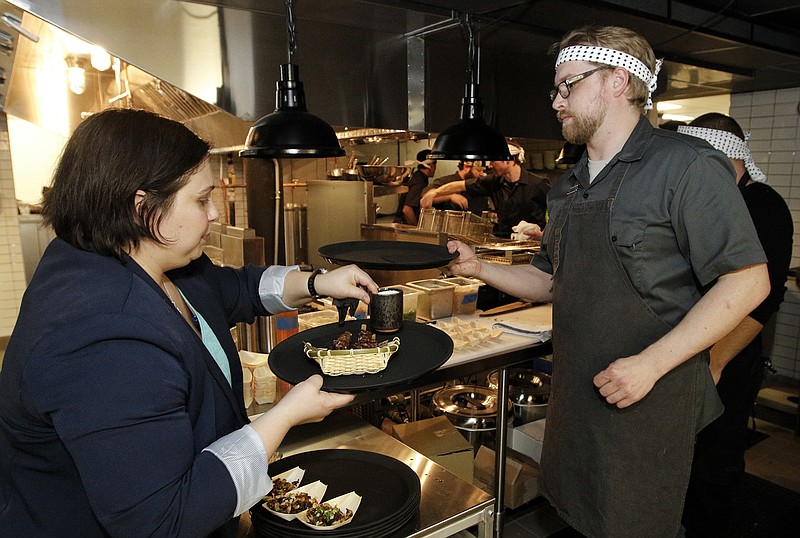 Chef George MacEwan, right, and operating partner Jessica Benefield plate food in the kitchen during a VIP event at new restaurant Two Ten Jack located in Warehouse Row in Chattanooga.