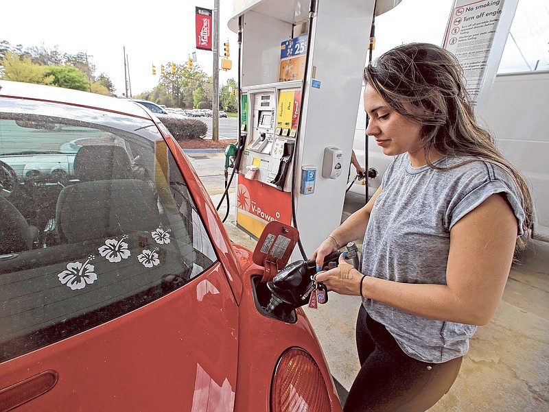 Lucy Perez, of Charlotte, N.C., pumps gas at a station in Matthews, N.C. Drivers will see the lowest summer gasoline prices in about six years, according to an Energy Department report released Tuesday.