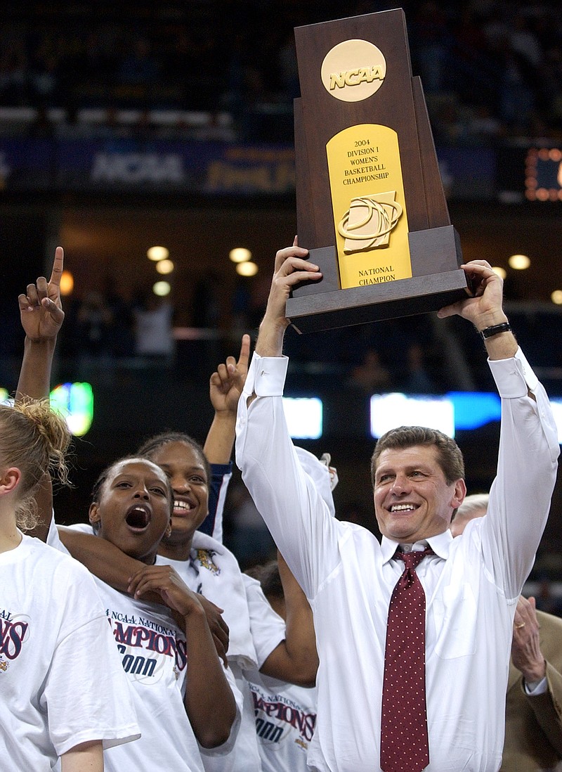 
              FILE - In this April 6, 2004, file photo, Connecticut coach Geno Auriemma hoists the championship trophy after UConn beat Tennessee 70-61 in the NCAA Division 1 Women's championship game in New Orleans. Auriemma could win his 10th championship and the tie the record held by former UCLA coach John Wooden with a win Tuesday night, April 7, 2015, against Notre Dame. (AP Photo/Mark Humphrey, File)
            