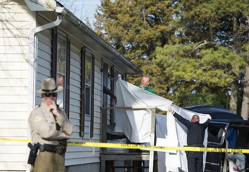 Sheets are held as a body is removed from a residence where police say seven children and one adult have been found dead Monday, April 6, 2015, in Princess Anne, Md. Officers were sent to the home Monday after being contacted by a concerned co-worker of the adult.