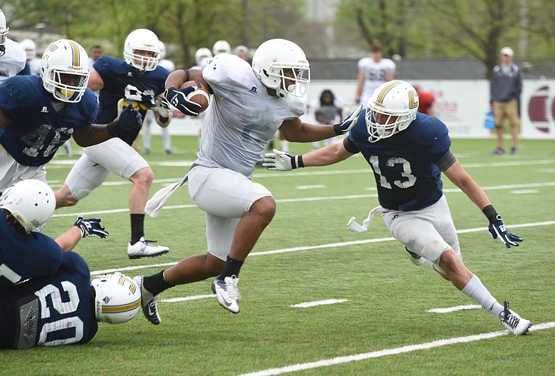 Moc's running back Shaqualm McCoy (2) breaks through the first line of defense but has to deal with Oscar Prado (13) on Friday, April 10, 2015, as the Chattanooga football players work in the second scrimmage of the spring Friday on the field at Chattanooga Christian School.
