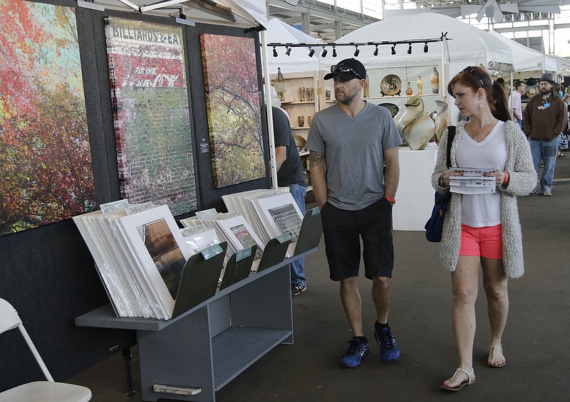 Billy Sergeant, left, and his wife Stephanie walk past art on display Saturday, April 11, 2015, at the 4 Bridges Art Festival at the First Tennessee Pavilion in Chattanooga. The annual show of fine arts and crafts drew 500 artists from across the country.