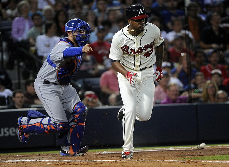 Atlanta Braves' Julio Teheran, right, runs to first after laying down a bunt as New York Mets catcher Travis d'Arnaud motions to throw him out during their game, Saturday, April 11, 2015, in Atlanta. 