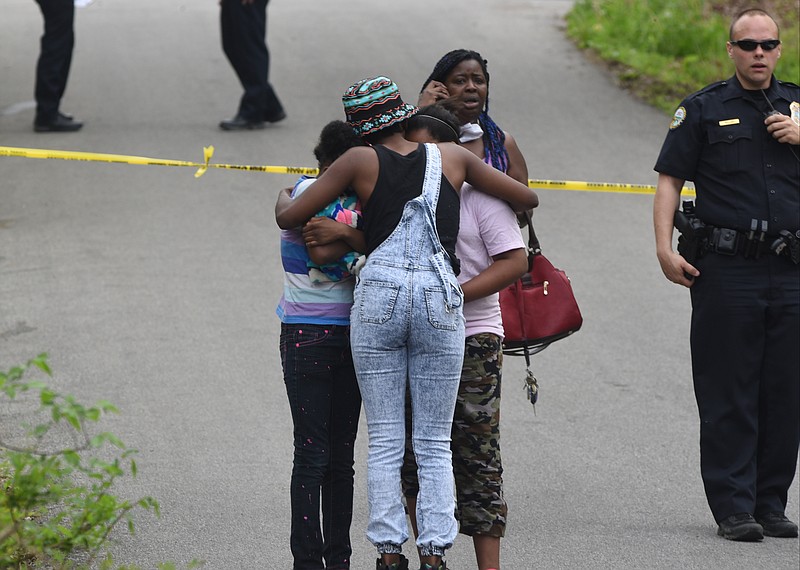 Theresa Provens, facing the camera, whose 16-year-old son Kenneth Provens was shot Sunday afternoon
at 825 N. Germantown Road, talks on her phone while others embrace at the scene Sunday.