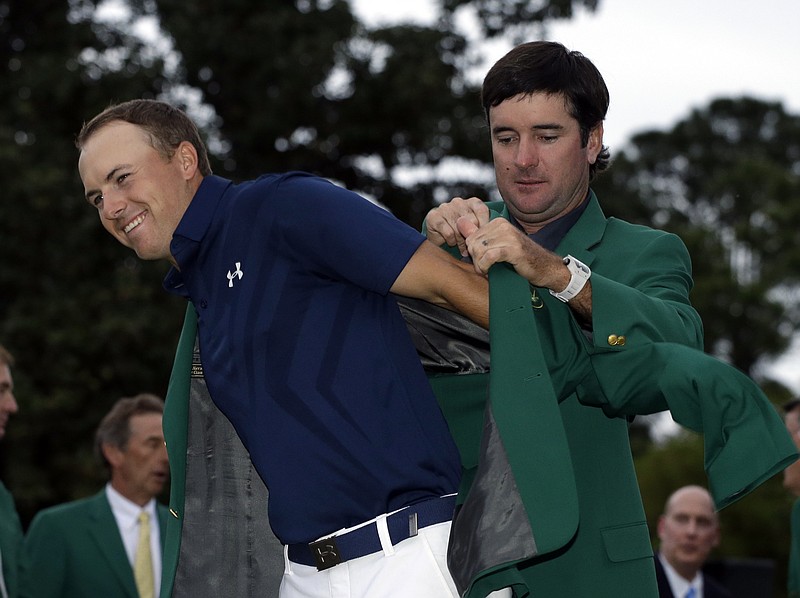 Bubba Watson helps Jordan Spieth put on his green jacket for the second time after winning the Masters golf tournament Sunday, April 12, 2015, in Augusta, Ga. 