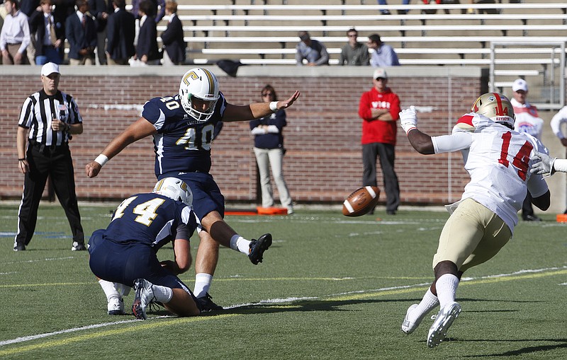 UTC's Toyvian Brand (#44) holds as Henrique Ribeiro (#40) kicks an extra point against VMI during the first quarter of play at the Moc's home field in Chattanooga on October 4, 2014.