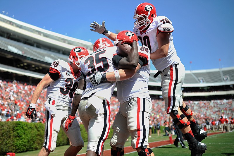 Black team players celebrate a touchdown against the Red team with running back A.J. Turman during Georgia's spring NCAA college football game Saturday, April 11, 2015, in Athens, Ga.