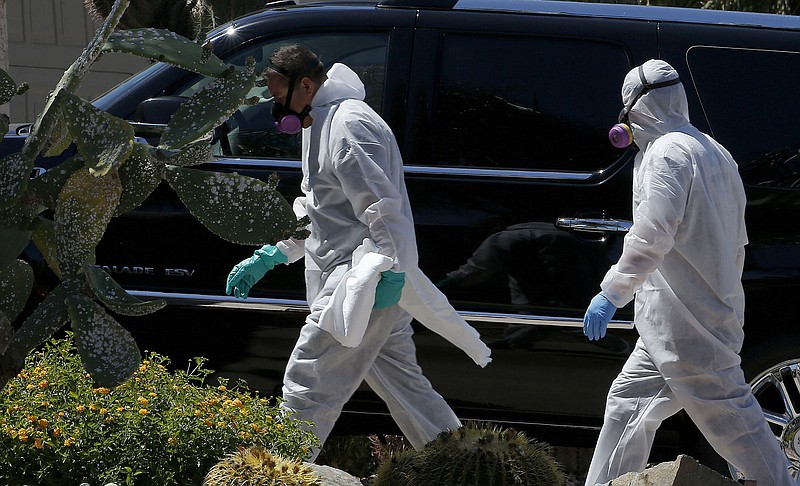 Members of a cleaning crew walk into a home after suiting up a day after five people were killed in a shooting inside, Friday, April 17, 2015, in Phoenix. 