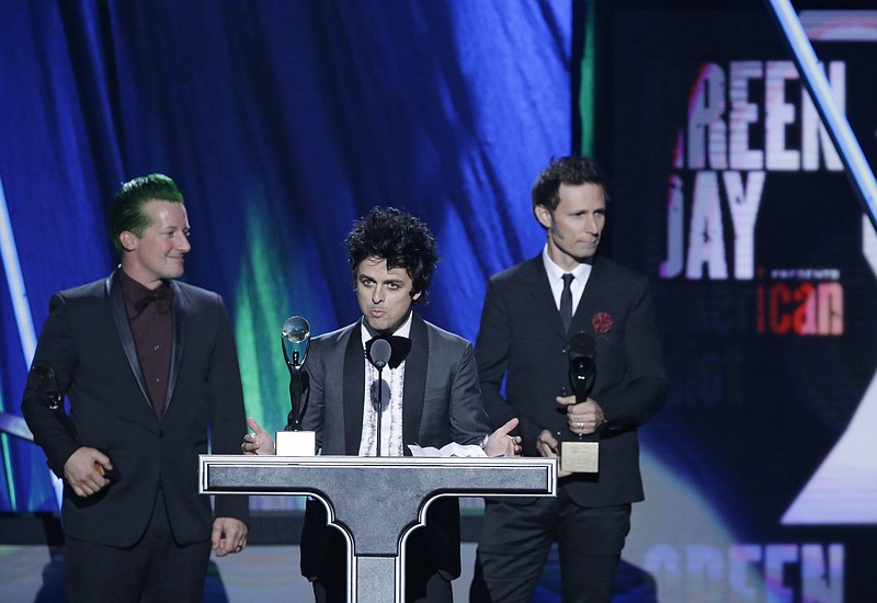 Billie Joe Armstrong speaks at the Rock and Roll Hall of Fame Induction Ceremony Saturday, April 18, 2015, in Cleveland, Ohio. Tre Cool, left, and Mike Dirnt, right, listen. 