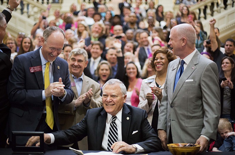 Georgia Gov. Nathan Deal, center, smiles after signing a medical marijuana bill into law during a ceremony at the Statehouse on April 16, 2015, in Atlanta. 