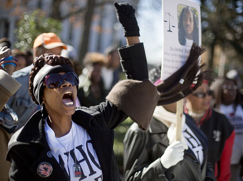 
              FILE - In this Dec. 11, 2013 file photo, Regina Rawls chants during a "Who Killed K.J." rally in memory of Kendrick Johnson, seen on the sign at right, in Atlanta. Long after Johnson was found dead inside a rolled-up gym mat at his high school in south Georgia, those closest to the case remain deeply divided over how the teenager died. (AP Photo/David Goldman, File)
            