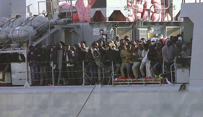 In this image from TV, migrants crowd at the rail aboard an Italian navy vessel as it cruises towards Italian port of Messina, on April 18, 2015. UNHCR says Sunday, April 19, 2015, the search and recovery rescue operation is under way after a boat carrying migrants overturned north of Libya.
