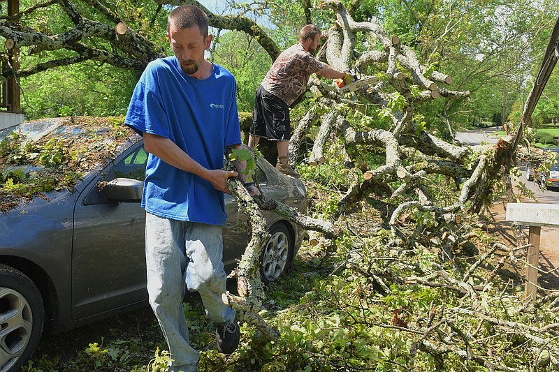 Timothy Tackett, left, and Ryan McClendon of Pro-Tree Service remove branches of a fallen oak tree at a house in the 400 block of Shallowford Road on Monday, Aug. 20, 2015, in Chattanooga after several rounds of storms on Sunday and Monday morning. The falling tree damaged a car and the front porch of the house, but barely missed the bedroom where two sleeping occupants escaped injury. 