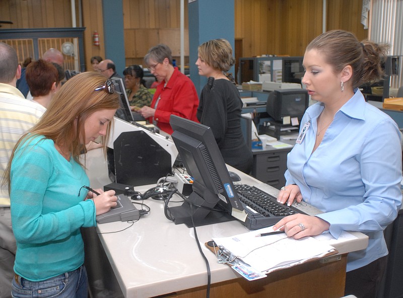 Megan McNabb, left, signs her name while renewing her drivers license at the Hamilton County Clerk's office in the Hamilton County Courthouse on Monday afternoon. Brooke Riker, deputy clerk, right, waits to finish processing the renewal.