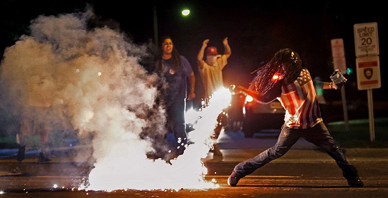 This August 13, 2014, photo by St. Louis Post Dispatch photographer Robert Cohen shows Edward Crawford returning a tear gas canister fired by police who were trying to disperse protesters in Ferguson, Missouri. 