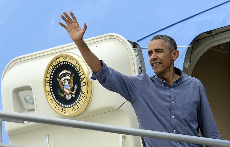 President Barack Obama waves after walking up the steps of Air Force One at Miami's International Airport, on Wednesday, April 22, 2015. 