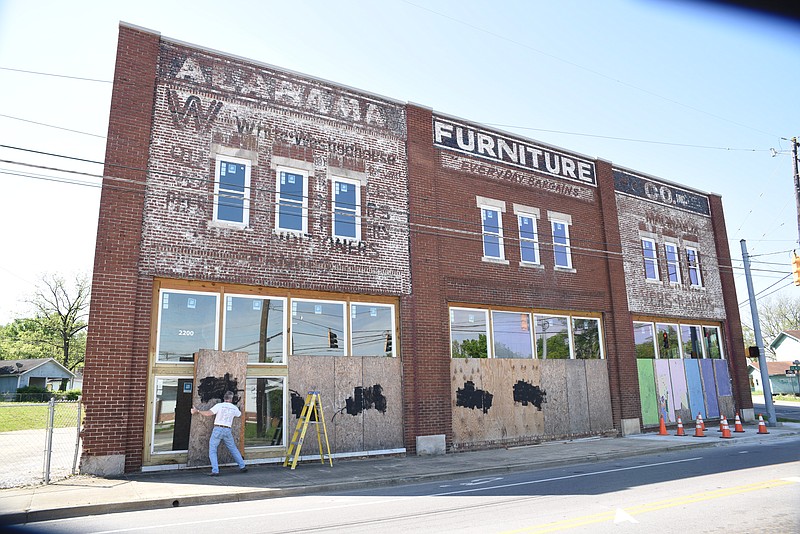 Building owner Towson Engsberg removes plywood covering from the former Alabama Furniture store at the corner of Dodson and Glass streets on Wednesday, April 22, 2015.