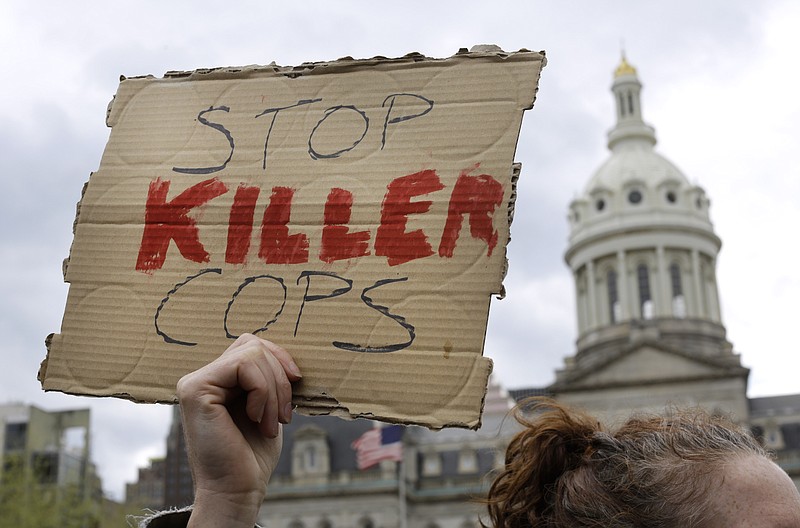 A protestor holds a sign outside of Baltimore's City Hall before a march for Freddie Gray, Thursday, April 23, 2015, in Baltimore. Gray died from spinal injuries about a week after he was arrested and transported in a police van.