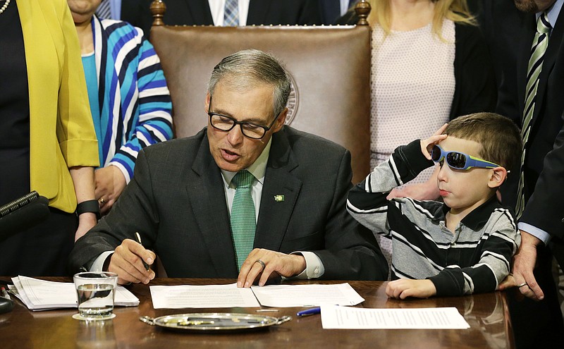 
              Haiden Day, 6, right, who has Dravet Syndrome, a form of epilepsy that his parents treat with medical marijuana, looks on as Washington Gov. Jay Inslee, left, signs a bill Friday, April 24, 2015 at the Capitol in Olympia, Wash., that overhauls Washington's medical marijuana market. The bill also creates a voluntary database of patients and cracks down on unregulated dispensary sales. Inslee has said the measure is needed now that the state's voter-approved recreational market is in place. (AP Photo/Ted S. Warren)
            