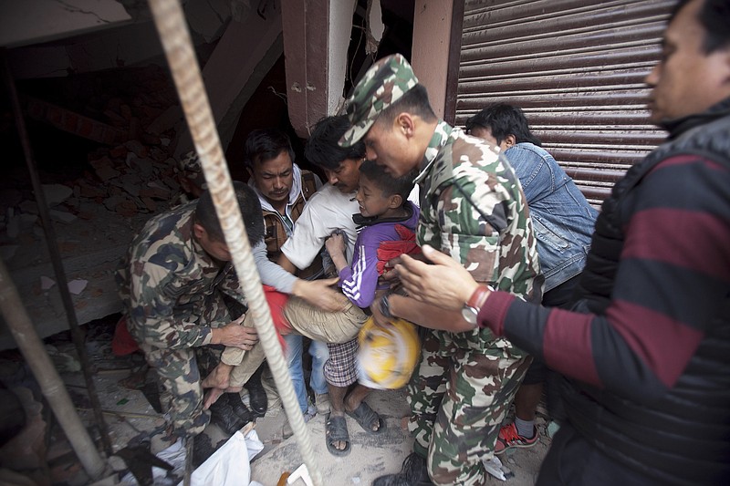 Volunteers carry an injured boy after rescuing him from the debris of a building that was damaged in an earthquake in Kathmandu, Nepal, Saturday, April 25, 2015. 